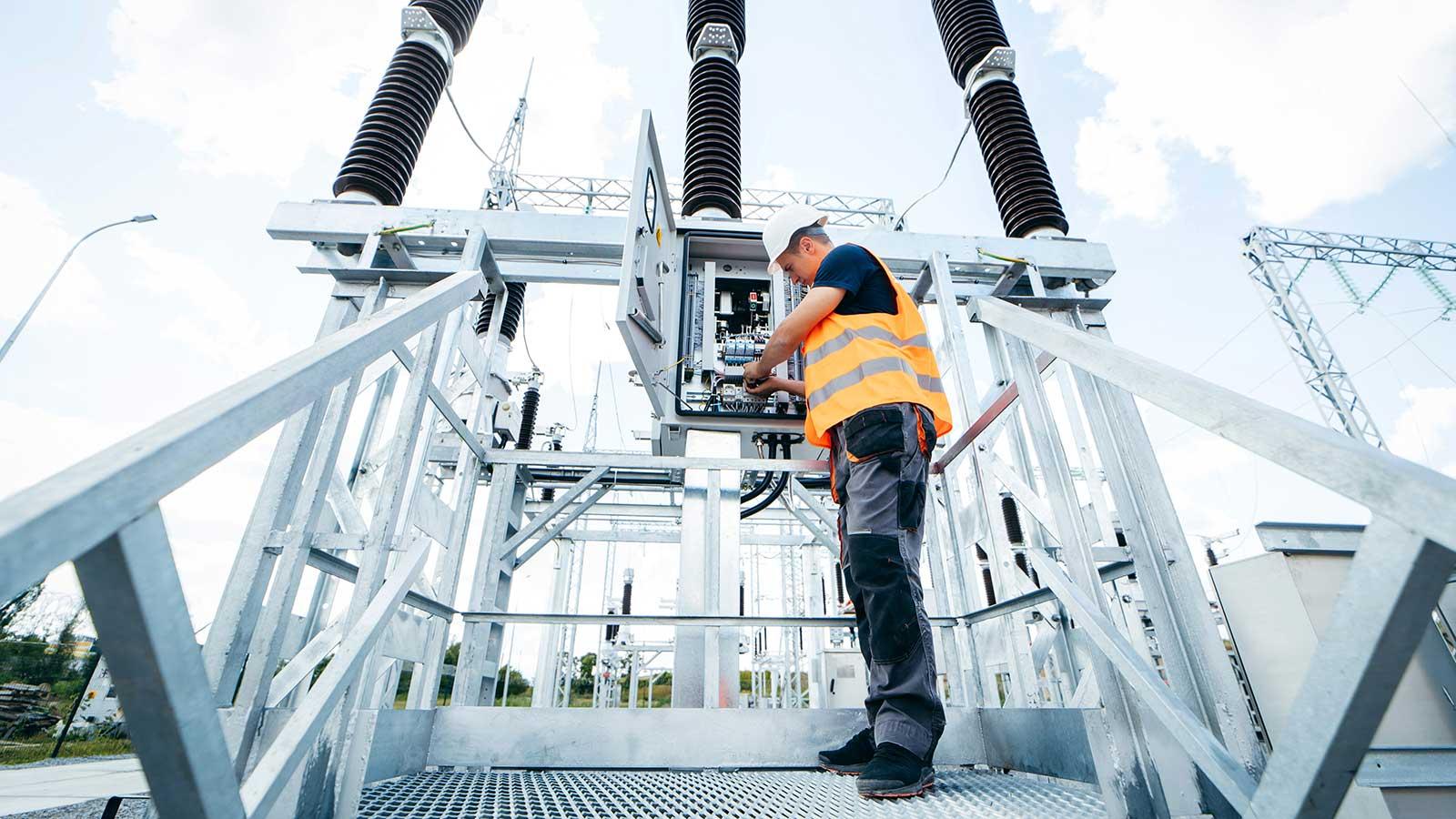 Worker with tools on electric tower representing Electrical-Engineering at Clarkson